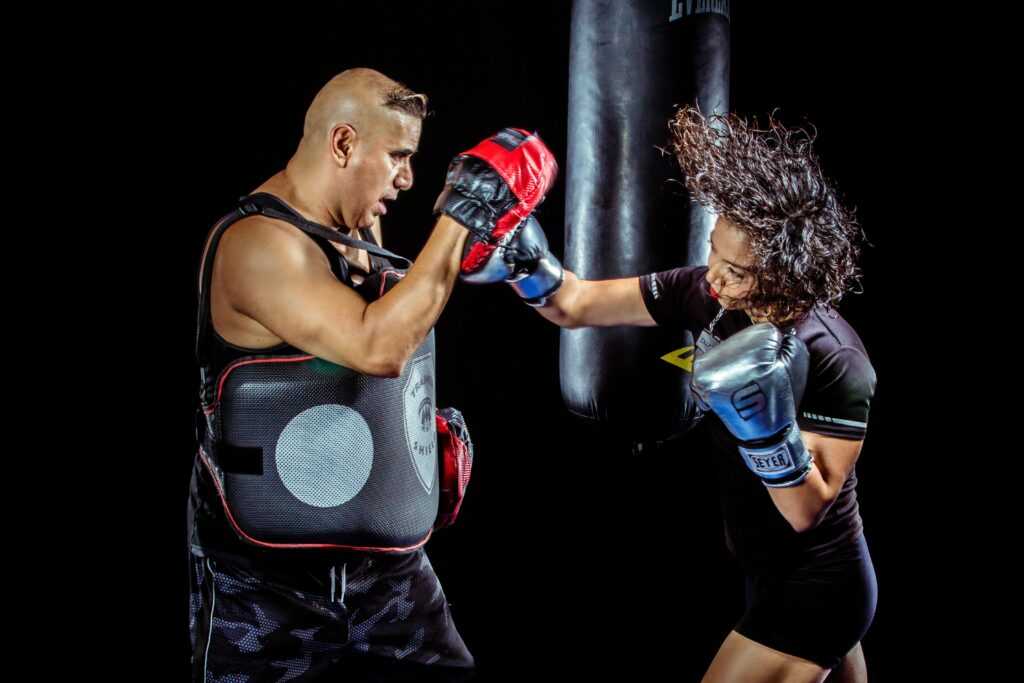 A woman boxing with a trainer in a gym, showcasing strength and focus.